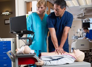 A person practices high-quality CPR with a nursing colleague on an adult mannequin.
