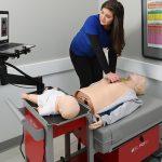 A health care provider demonstrates CPR on a manikin.