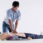 A healthcare trainer performing CPR training on an adult medical simulation manikin for a community advocacy program.