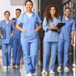 A group of nursing students walk in a hospital hallway.