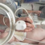 Clinician performing a cardiac ultrasound on a newborn in a neonatal care unit