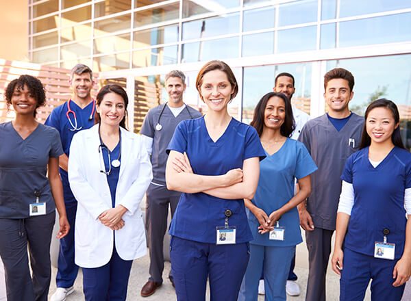 Nurses stand proud together in front of their hospital.