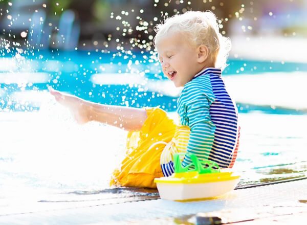 A toddler plays on the edge of a pool.