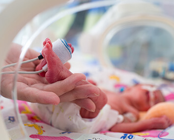 Mother holding premature baby legs with neonatal infant pulse oximeter Mother holding premature baby legs with neonatal infant pulse oximeter
